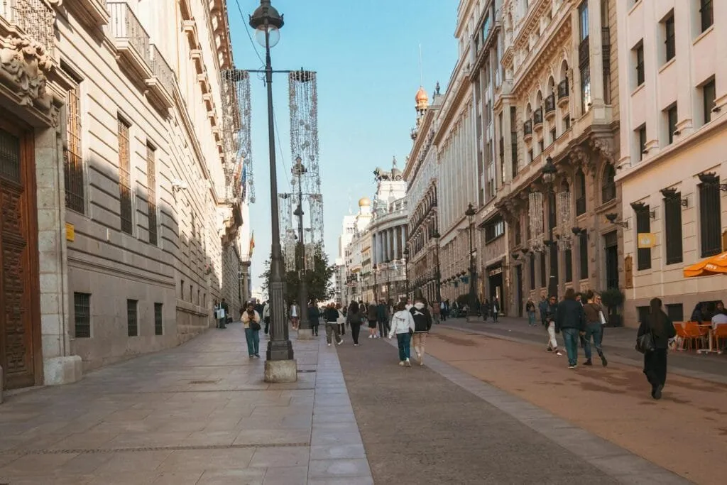 People walking down a vibrant European street lined with historic buildings on a sunny day.